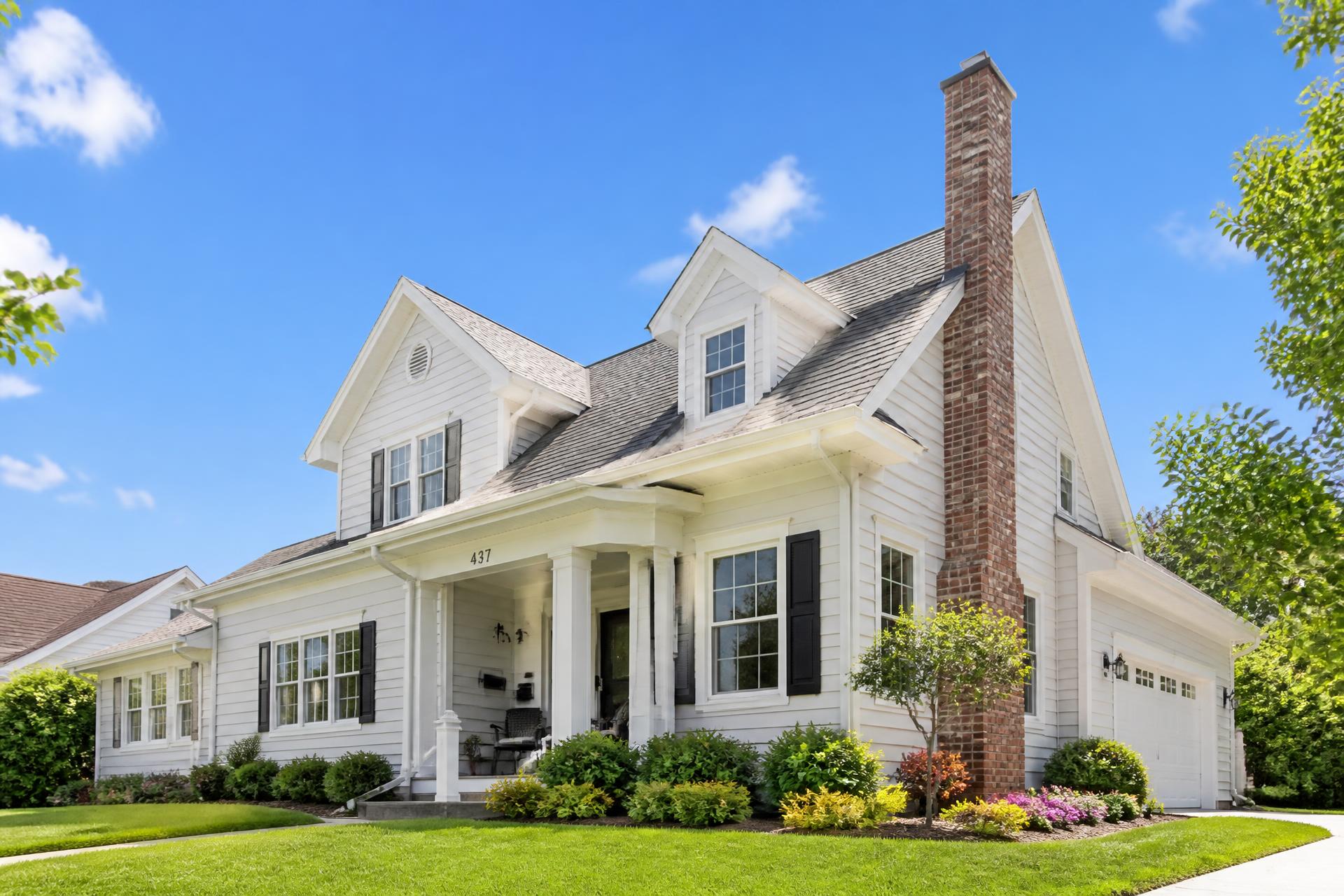 Suburban home with a clean brick chimney against a bright blue sky in Manhasset, New York
